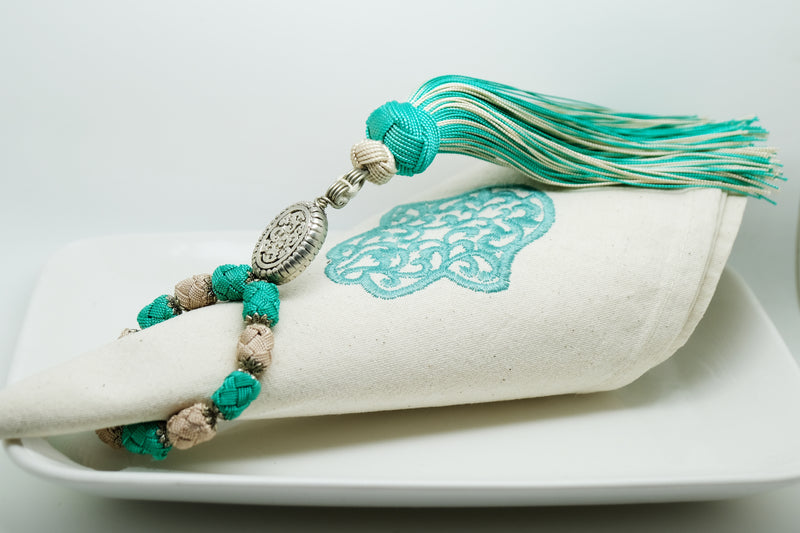 SET OF FOUR TURQUOISE & BEIGE EMBROIDERED NAPKINS AND TASSEL RINGS