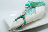 SET OF FOUR TURQUOISE & BEIGE EMBROIDERED NAPKINS AND TASSEL RINGS